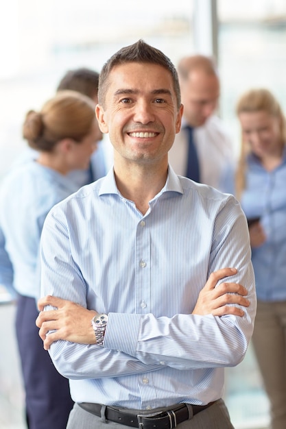 Foto conceito de negócios, pessoas e trabalho em equipe - empresário sorridente com grupo de empresários reunidos no escritório