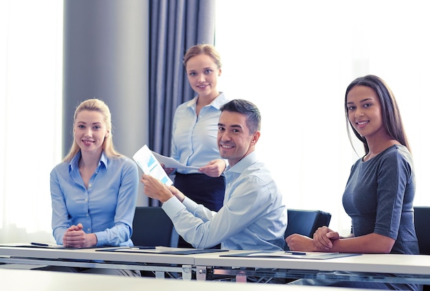 conceito de negócios, pessoas e trabalho em equipe - equipe de negócios sorridente com documentos reunidos no escritório