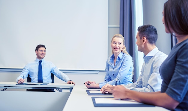 conceito de negócios, pessoas e trabalho em equipe - grupo de empresários sorridentes reunidos no escritório