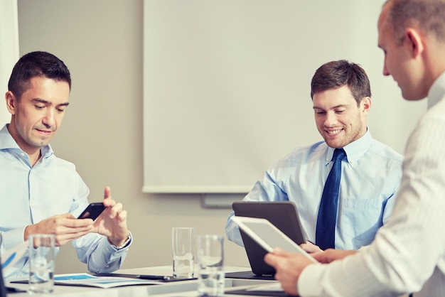 Foto conceito de negócios, pessoas, tecnologia e trabalho em equipe - empresários sorridentes com computadores smartphone e tablet pc reunidos no escritório