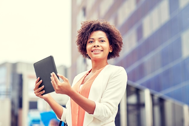 conceito de negócios, tecnologia, comunicação e pessoas - jovem empresária afro-americana sorridente com computador tablet pc na cidade