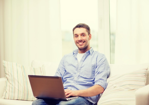conceito de negócios, tecnologia e e-learning - homem sorridente trabalhando com laptop em casa