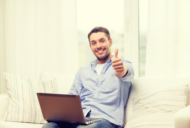 conceito de negócios, tecnologia e e-learning - homem sorridente trabalhando com laptop em casa