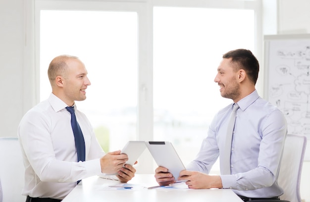 conceito de negócios, tecnologia e escritório - dois empresários sorridentes com computadores tablet pc e arquivos no escritório