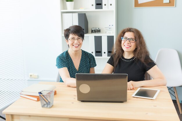 Conceito de negócios, tecnologia e pessoas - mulher mostra seu projeto no laptop outra mulher.