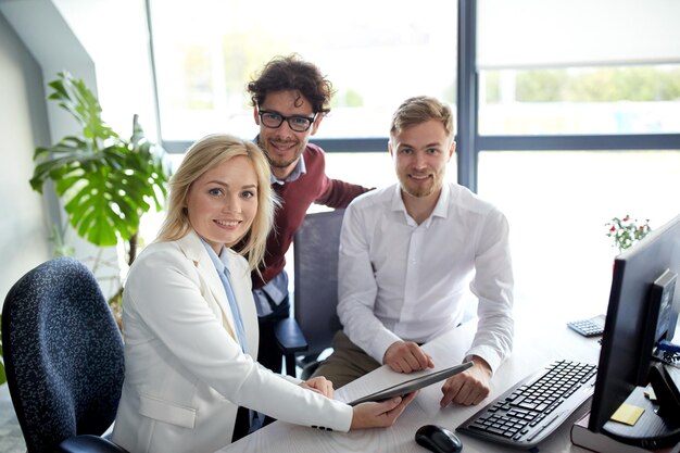 conceito de negócios, tecnologia, pausa e pessoas - equipe criativa feliz com computador tablet pc no escritório