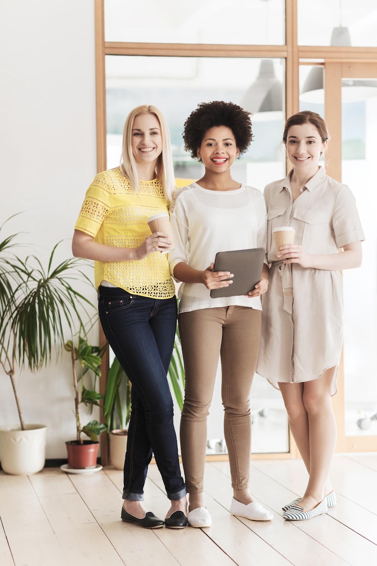 Foto conceito de negócios, tecnologia, pessoas e trabalho em equipe - feliz equipe criativa internacional de três mulheres com computador tablet pc e café no escritório