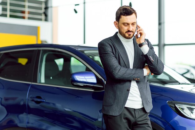 Conceito de negócios, venda de carros, consumismo e pessoas - homem feliz com salão de automóveis ou salão de beleza