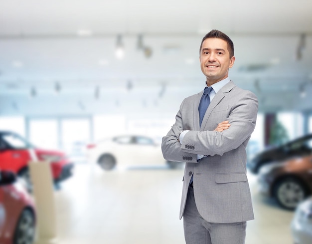 Conceito de negócios, venda de carros, consumismo e pessoas - homem feliz com salão de automóveis ou salão de beleza