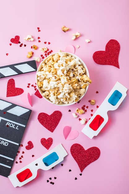 Conceito de noite de filme de São Valentim. Pipoca, claquete de óculos 3d em fundo rosa. Planos de férias aconchegantes para os amantes