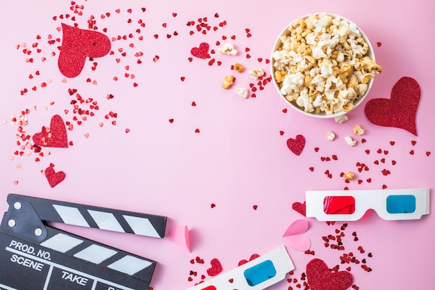 Conceito de noite de filme de São Valentim. Pipoca, claquete de óculos 3d em fundo rosa. Planos de férias aconchegantes para os amantes