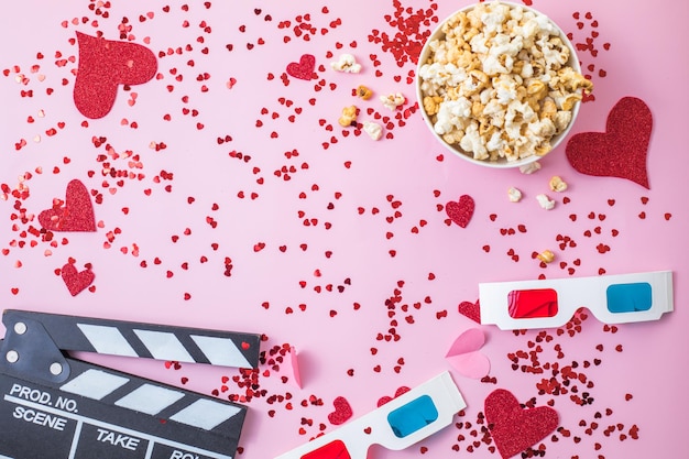 Conceito de noite de filme de São Valentim. Pipoca, claquete de óculos 3d em fundo rosa. Planos de férias aconchegantes para os amantes