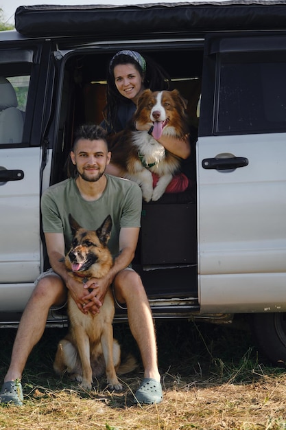 Conceito de nômade digital com pessoas caucasianas em viagem romântica em minivan Casal com cachorros