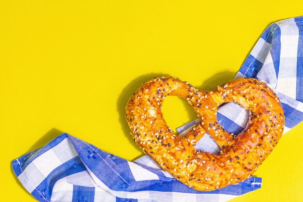 Conceito de Oktoberfest - pretzel em um guardanapo tradicional. Luz dura na moda, sombra escura. Fundo amarelo pastel, vista superior