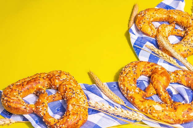 Conceito de Oktoberfest - pretzels em um guardanapo tradicional. Luz dura na moda, sombra escura. Espiguetas secas, fundo amarelo pastel, espaço de cópia