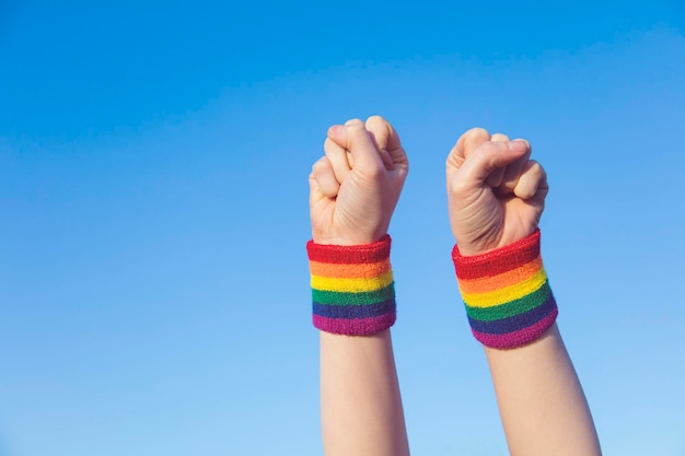 Conceito de orgulho gay Mão fazendo um sinal de punho com a pulseira da bandeira do arco-íris LGBT do orgulho gay