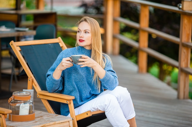 Conceito de outono - mulher bonita tomando café no parque outono sob folhagem de outono