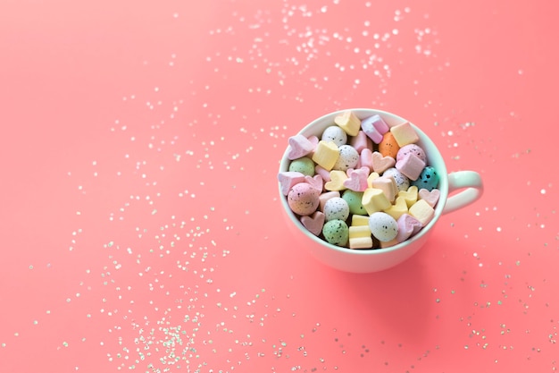 Conceito de Páscoa Doces doces e marshmallows em um copo em um fundo rosa