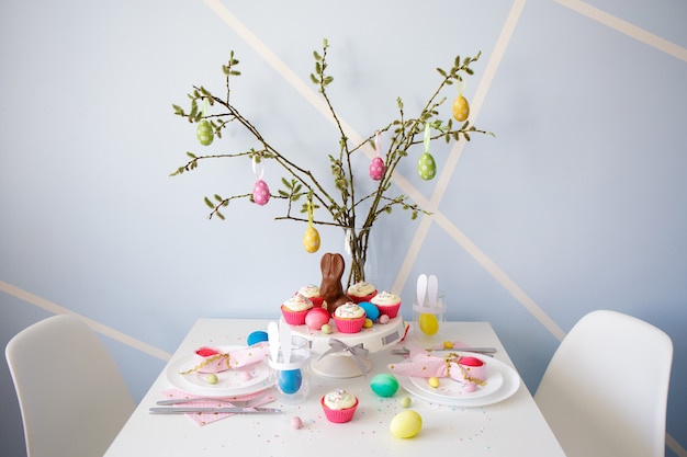 Conceito de Páscoa - mesa decorada com cupcakes, ovos coloridos e coelhinhos pintados