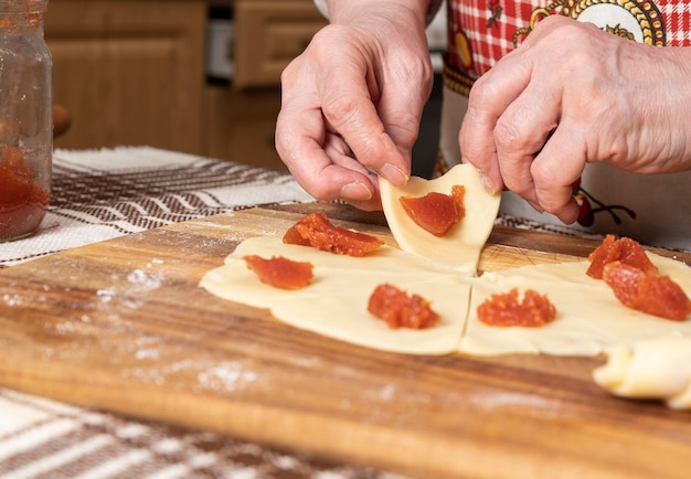 Conceito de pastelaria e panificação. Mulher preparando pãezinhos caseiros com geléia em casa