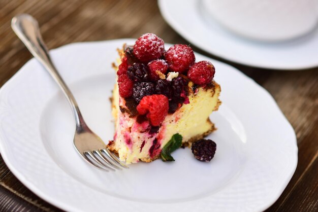 Conceito de pastelaria Pedaço de bolo com amoras e framboesas