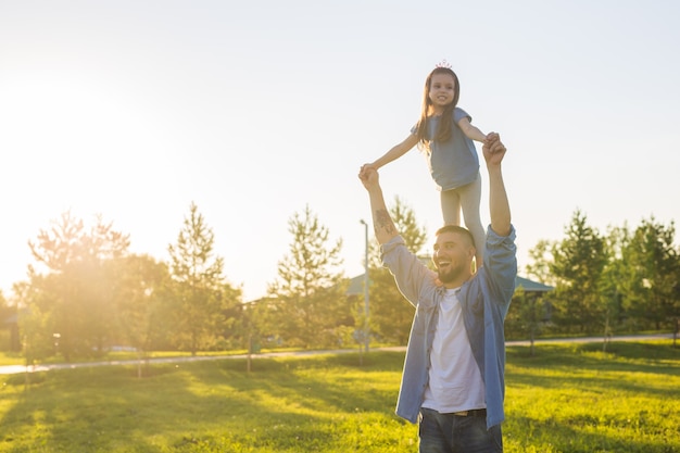 Conceito de paternidade, família e filhos - pai e filha se divertindo e brincando na natureza.