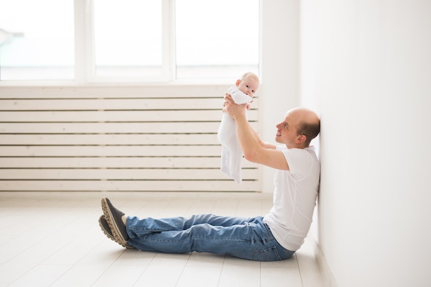 Conceito de paternidade, família e paternidade. pai careca sentado no chão segurando seu bebezinho