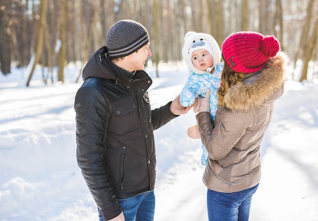 Conceito de paternidade, moda, temporada e pessoas - família feliz com criança em roupas de inverno ao ar livre.