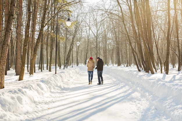 Conceito de paternidade, moda, temporada e pessoas - família feliz com criança em roupas de inverno ao ar livre.