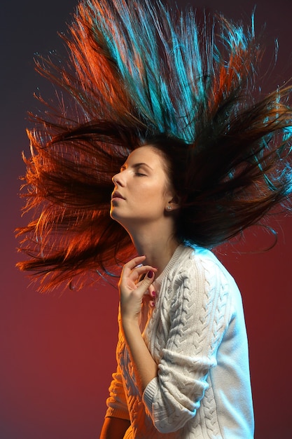 Conceito de penteado da moda. Mulher jovem com cabelos coloridos tingidos na parede colorida