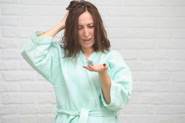 Foto conceito de perda de cabelo mulher jovem preocupada segurando um monte de cabelo caído na mão enquanto estava perto de branco