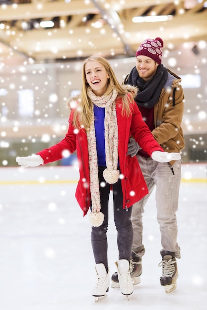 conceito de pessoas, amizade, esporte e lazer - casal feliz na pista de patinação