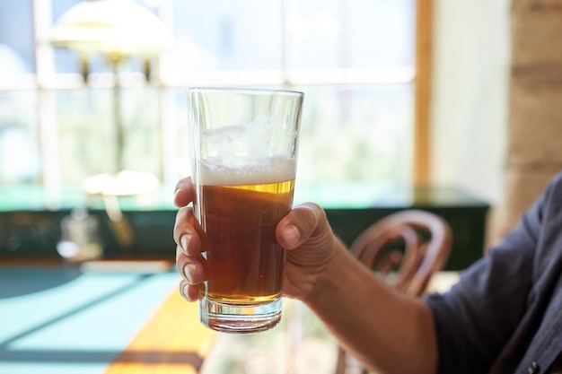 conceito de pessoas, bebidas, álcool e lazer - close-up do homem bebendo cerveja de vidro no bar ou pub