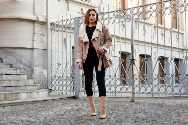 Conceito de pessoas, beleza, moda, estilo de vida e cor - retrato de corpo inteiro ao ar livre da bela jovem sorridente feliz posando na rua. modelo olhando para a câmera. senhora vestindo roupas elegantes de inverno