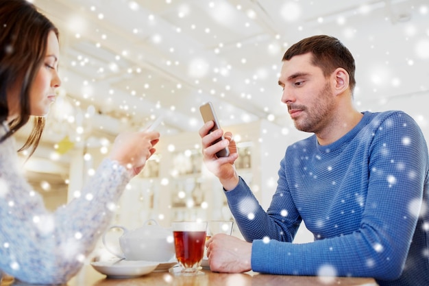 conceito de pessoas, comunicação e namoro - casal com smartphones bebendo chá no café ou restaurante