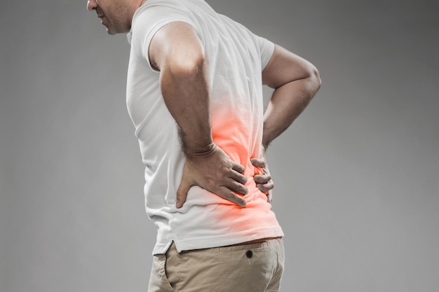 Foto conceito de pessoas, cuidados de saúde e problemas - close-up do homem que sofre de dor nas costas ou rédeas sobre fundo cinza