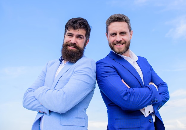 Conceito de pessoas de negócios Empresários barbudos posando com confiança Homens de negócios ficam fundo de céu azul Perfeito em todos os detalhes A aparência bem cuidada melhora a reputação do negócio empresário