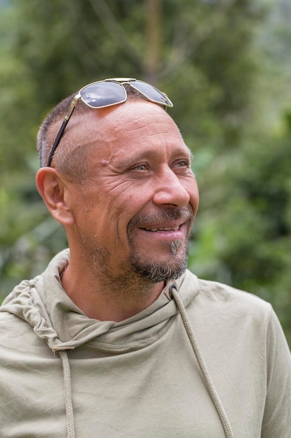 Conceito de pessoas e estilo de vida Feliz homem não barbeado de meia-idade ao ar livre contra o fundo verde da natureza Retrato de homem adulto closeup