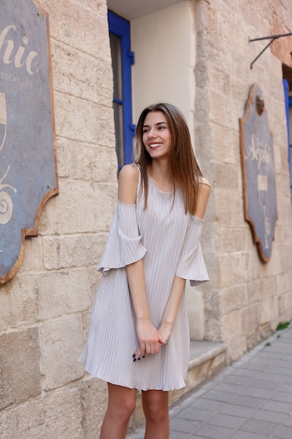 Conceito de pessoas, emoções, natural, beleza e estilo de vida - jovem bela mulher alegre andando na velha rua na cidade tropical. Menina bonita olhando para você e sorrindo