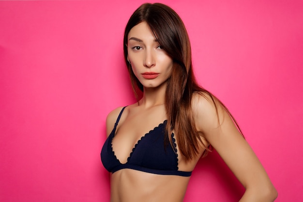 Conceito de pessoas, emoções, natural, beleza e estilo de vida - jovem mulher sexy em lingerie posando em fundo rosa