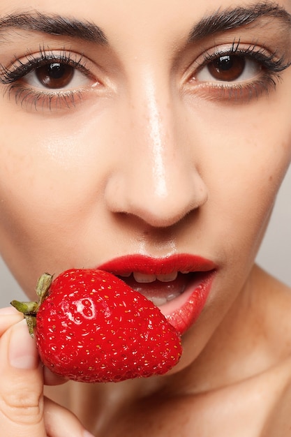 Foto conceito de pessoas, emoções, natural, comida, beleza e estilo de vida - mulher sexy comendo morango. lábios sensuais. manicure e batom. desejo. lábios sensuais de beleza garota com morango. dente branco