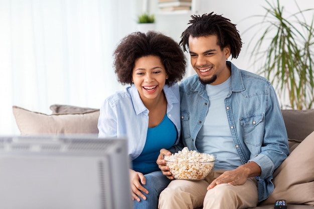 Foto conceito de pessoas, família e lazer - casal sorridente com pipoca assistindo tv em casa