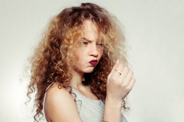 Foto conceito de pessoas, juventude e beleza - mulher de beleza com cabelo comprido e encaracolado. cabelo com permanente. senhora do glamour, fundo cinza da menina da beleza. retrato de mulher bonita. cabelo loiro ondulado. cabelo de menina infeliz