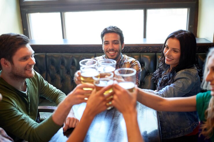Foto conceito de pessoas, lazer, amizade e celebração - amigos felizes bebendo chope e tilintar de copos em bar ou pub