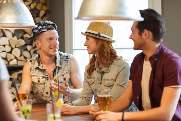 Foto conceito de pessoas, lazer, amizade e comunicação - grupo de amigos sorridentes felizes bebendo cerveja e coquetéis no bar ou pub