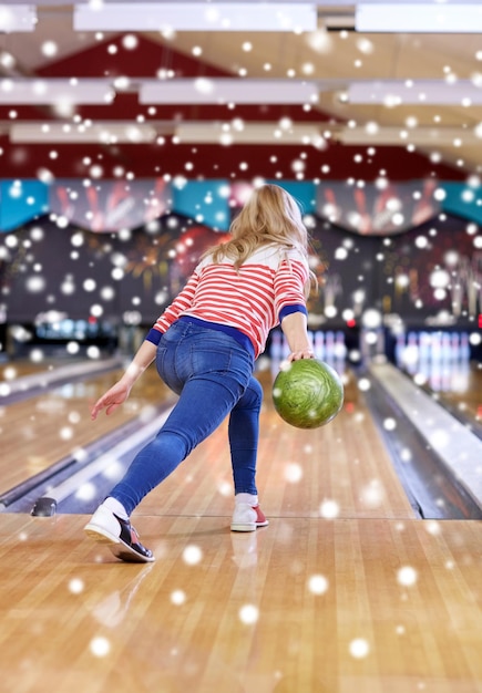 Conceito de pessoas, lazer, esporte e entretenimento - jovem feliz jogando bola no clube de boliche na temporada de inverno