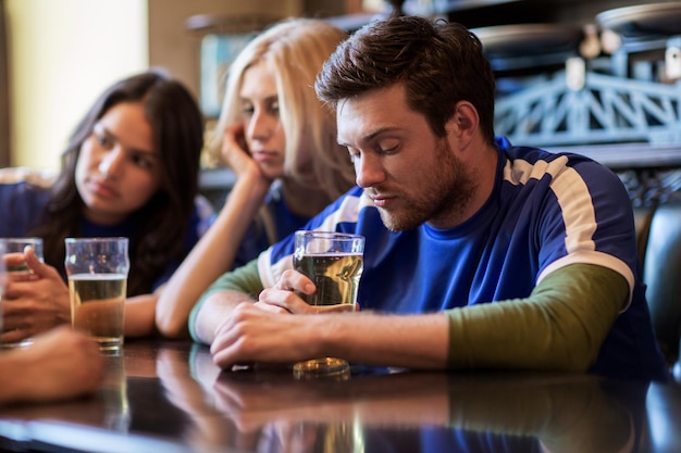 conceito de pessoas, lazer, futebol e esporte - fãs de futebol infelizes ou amigos com cerveja no bar ou pub