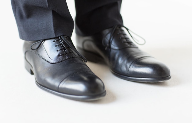 conceito de pessoas, negócios, moda e calçados - close-up das pernas do homem em sapatos elegantes com cadarços ou botas de renda