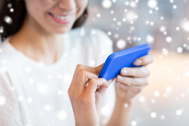 conceito de pessoas, tecnologia e estilo de vida - close-up de mulher com smartphone no café sobre efeito de neve