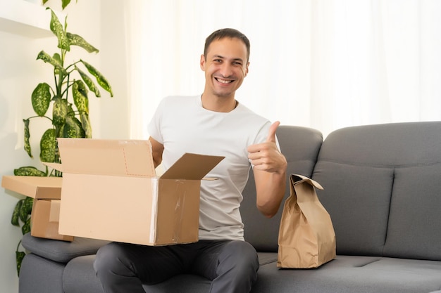 conceito de postagem, casa e estilo de vida - homem sorridente com caixas de papelão em casa